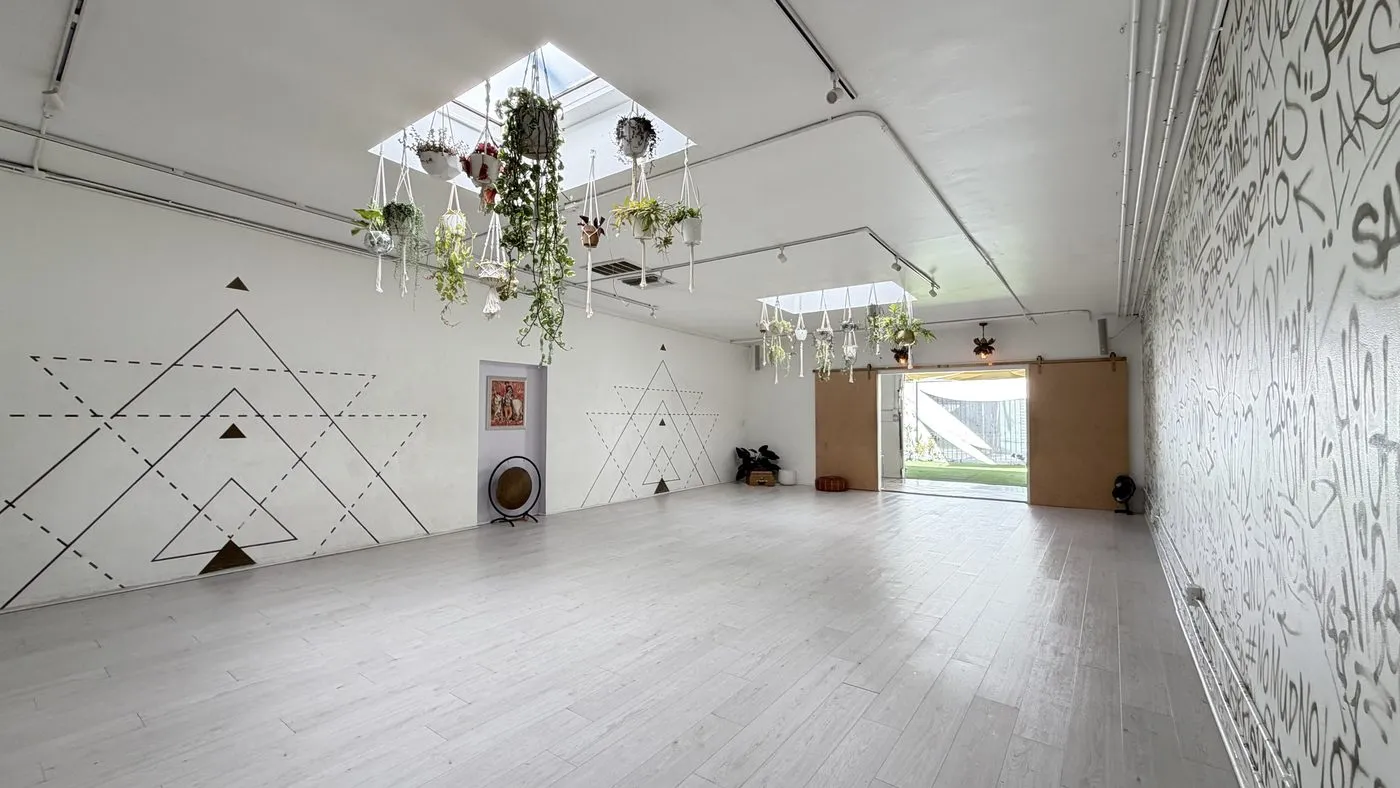 The main room seen along its length, the hand-lettered wall on the right, line-drawn triangles on the left and the open barn doors to the garden at the far end