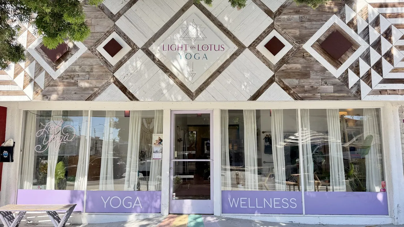 The storefront on Venice Boulevard, a facade of whitewashed and natural wood boards in a diamond pattern with a sign reading Light Lotus Yoga, above curtained windows lettered Yoga and Wellness on lavender panels