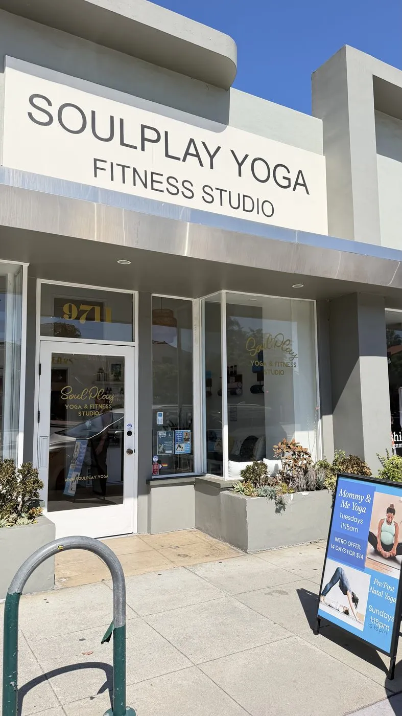 The entrance close up, the Soulplay Yoga Fitness Studio sign above the glass door with a pavement A-board beside it