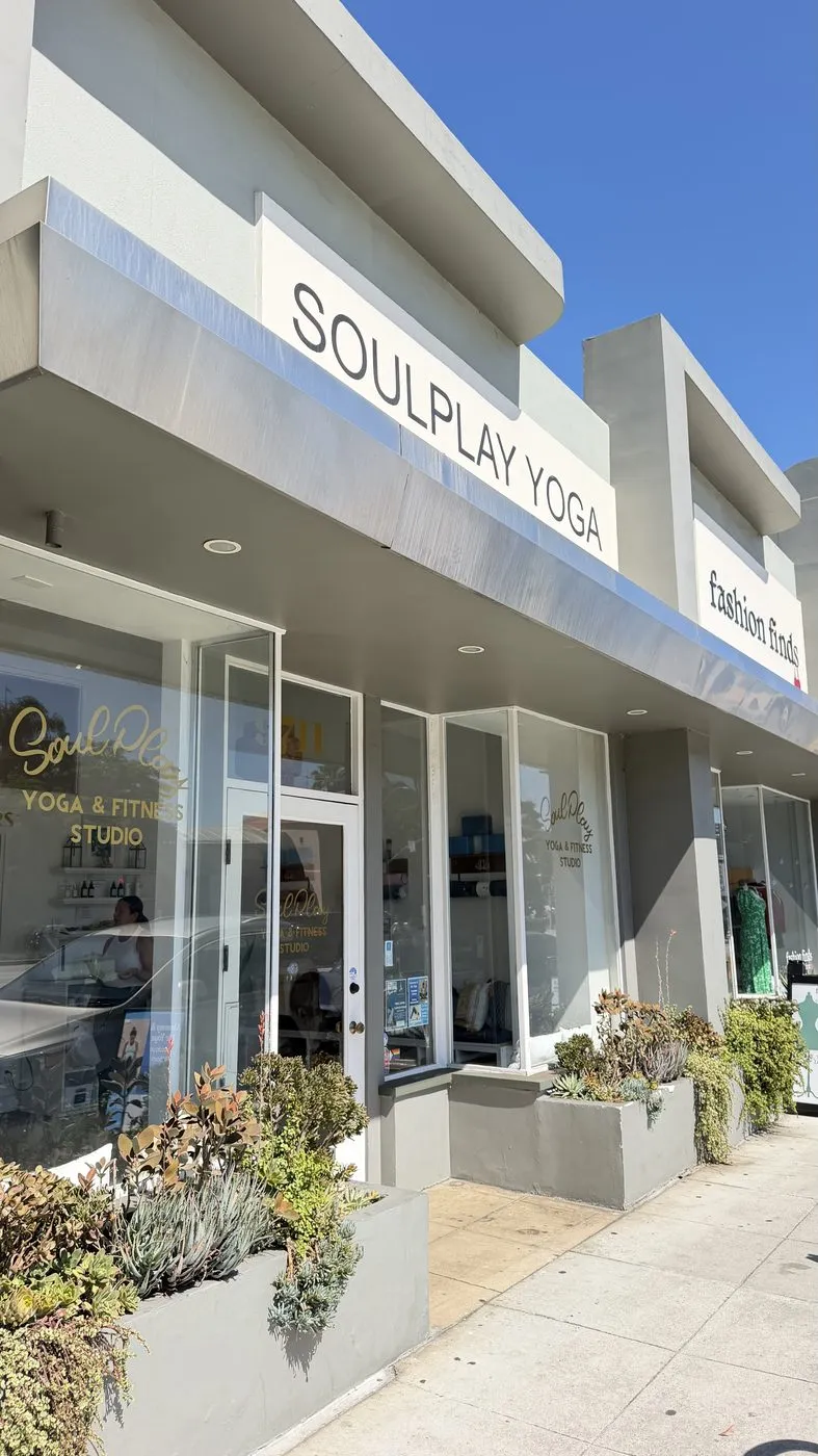 The frontage at an angle, the studio sign along the top of the glass and planted succulents running the length of the pavement